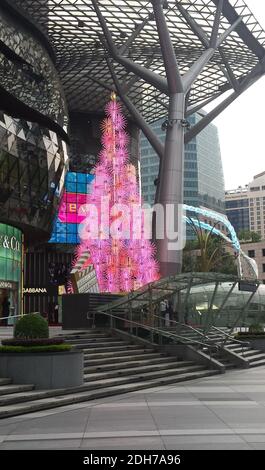 SINGAPUR, SINGAPUR - 11. Nov 2019: Ein elektrischer Weihnachtsbaum in Pink, beleuchtet am Tag vor einer Mall für Top-Marken an der Orchard Road Stockfoto