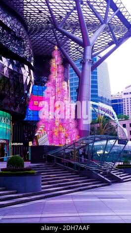 SINGAPUR, SINGAPUR - 11. Nov 2019: Ein elektrischer Weihnachtsbaum in Pink, beleuchtet am Tag vor einer Mall für Top-Marken an der Orchard Road Stockfoto