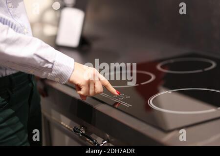 Weibliche Finger drückt Taste auf Touch-Elektroherd Stockfoto