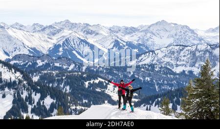 Seniorenpaar ist Schneeschuhwandern im alpinen Schnee Winter Berge Panorama. Glückliche erfolgreiche Menschen mit ausgestreckten Armen. Allgau, Bayern, Deutschland. Stockfoto