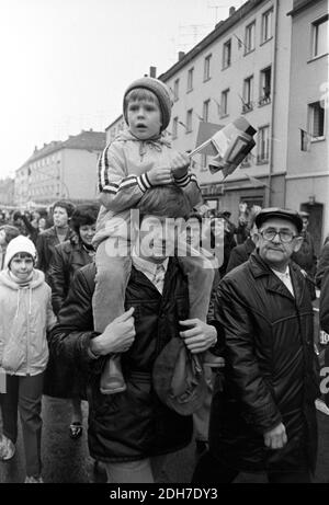 01. Mai 1982, Sachsen, Eilenburg: Kind auf den Schultern des Vaters mit DDR-Papierfahnen. Bei der Demonstration in Eilenburg am 1. Mai 1982 marschieren Arbeiter, Schüler, Sportler und Kinder am Rathaus und einer Tribüne mit Ehrengästen vorbei. Foto: Volkmar Heinz/dpa-Zentralbild/ZB Stockfoto