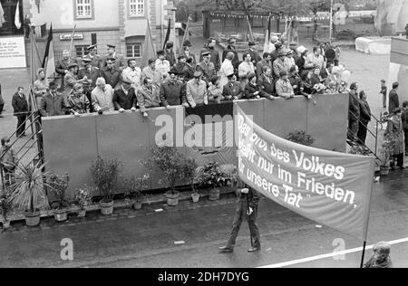 01. Mai 1982, Sachsen, Eilenburg: "Das Brot des Volkes blüht nur in Frieden für das, was wir getan haben." Während der Demonstration am 1. Mai 1982 in Eilenburg marschieren Arbeiter, Schüler, Sportler und Kinder vor dem Rathaus der Stadt, mit dem Ratskeller und einer Tribüne mit Ehrengästen davor. Foto: Volkmar Heinz/dpa-Zentralbild/ZB Stockfoto