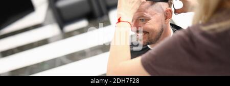 Junger gutaussehender lächelnder Mann sitzt im Friseurstuhl und tut Hochformat waschen Stockfoto