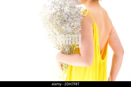 Unkenntlich weiblich in leuchtenden gelben Kleid versteckt hinter Bouquet von wildblumen am Sommertag vor weißem Hintergrund Stockfoto