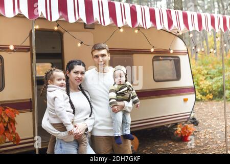 Porträt einer jungen lächelnden Familie, während sie sich in der Nähe des Hauses umarmte Auf Rädern Stockfoto