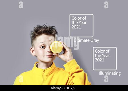 Ein Junge in einem hellen gelben Jacke mit einer Zitrone in der Hand auf einem blauen Hintergrund Stockfoto