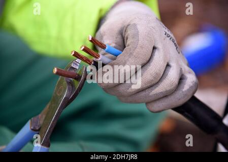 Arbeiter auf einer Baustelle, Straßenbeleuchtung. Konzentrieren Sie sich auf Handschuhen, Zangen und elektrische Kupferkabel Stockfoto