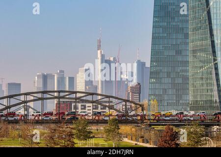 Güterzug mit vielen Autos über die Eisenbahnbrücke mit der Frankfurter Skyline im Hintergrund in Frankfurt am Main, Hessen, Deutschland. Stockfoto