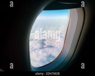 Bild mit geringer Schärfentiefe (selektiver Fokus) mit einem Flugzeugfenster und den Wolken draußen. Stockfoto