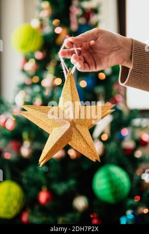 Hand hält goldene Sterne vor dem Weihnachtsbaum Stockfoto