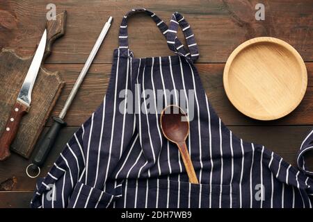 Blaue textile Küchenschürze mit weißen Streifen und Küchenutensilien, Draufsicht Stockfoto