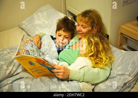 Großmutter liest den Enkelkindern vor dem Schlafengehen Stockfoto