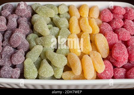 Eine Keramikschale voll von Leckereien nach Farbe angeordnet. Hoch in Zucker Lebensmittel Stockfoto