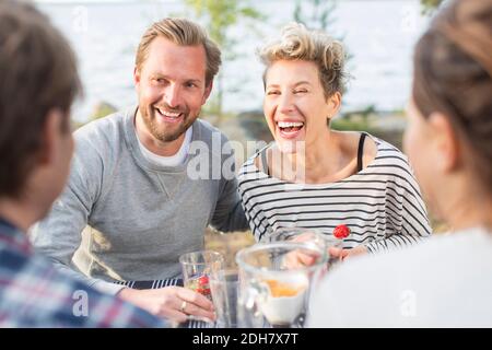 Glückliche Freunde genießen beim Mittagessen am Picknicktisch Stockfoto
