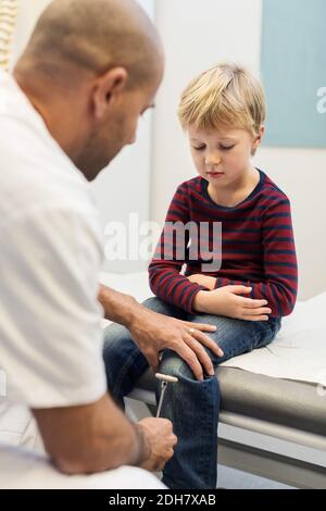 Arzt Überprüfung der Knie Reflexe des Jungen in der orthopädischen Klinik Stockfoto