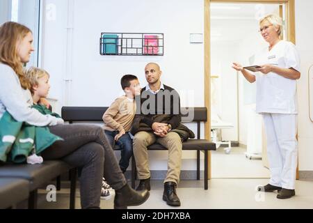 Krankenschwester im Gespräch mit Patienten sitzen im Warteraum bei orthopädischen Klinik Stockfoto
