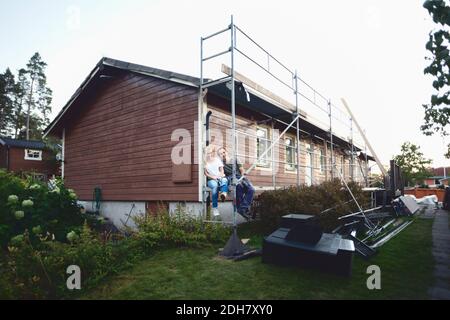 Ein glückliches Paar, das vor dem Haus sitzt und gerade renoviert wird Stockfoto