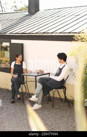 Kellnerin und Kellner machen Kaffeepause vor dem Restaurant Stockfoto