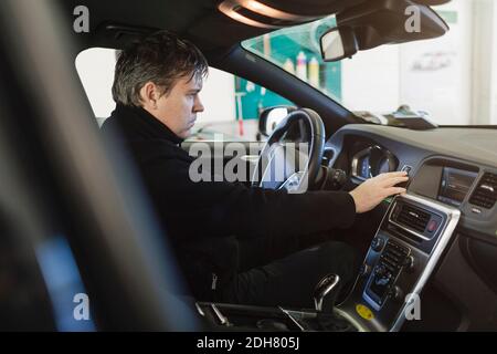 Seitenansicht des Mechanikers, der das Armaturenbrett im Auto untersucht Stockfoto