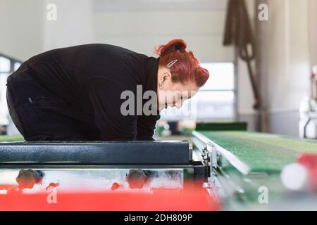 Seitenansicht der Mechanikerin mit hydraulischem Hub im Auto Reparaturwerkstatt Stockfoto