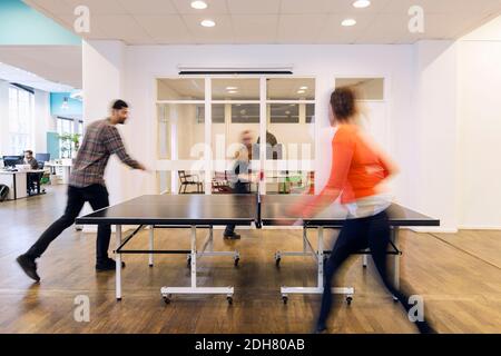 Verschwommene Bewegung von Geschäftsleuten, die Tischtennis spielen, in kreativen Büro Stockfoto