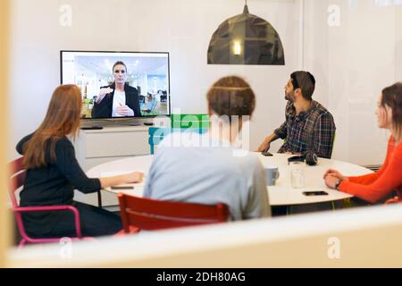 Kreative Geschäftsleute, die an einer Telefonkonferenz im Sitzungssaal teilnehmen Stockfoto