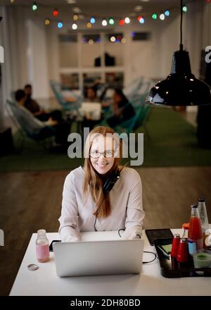 Porträt von lächelnden Geschäftsfrau arbeiten spät auf Laptop in kreativ Büro Stockfoto