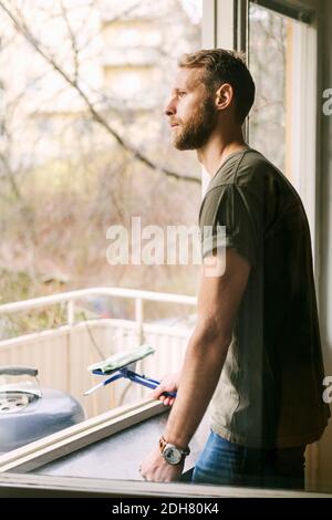 Seitenansicht eines durchdachten Mannes, der durch das Fenster schaute Stockfoto
