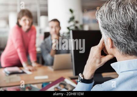 Beschnittenes Bild eines Geschäftsmannes, der mit Kollegen am Schreibtisch sitzt Hintergrund Stockfoto