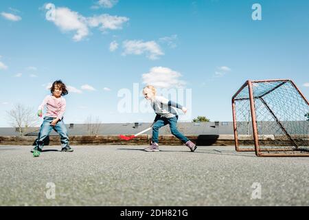 Kinder spielen Hockey auf dem Hof gegen blauen Himmel Stockfoto