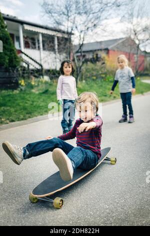 Kinder, die Freund Skateboard auf Fußweg außerhalb des Hauses Stockfoto