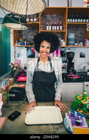 Porträt einer glücklichen Barista mit Serviertablett im Café Stockfoto