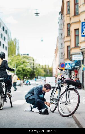 Geschäftsmann Reparatur Fahrrad auf der Straße Stockfoto