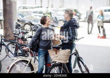 Glückliches Seniorenpaar mit Fahrrädern, die auf der Stadtstraße stehen Stockfoto