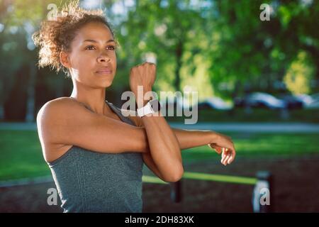 Frau trägt Smart Uhr Stretching im Park Stockfoto