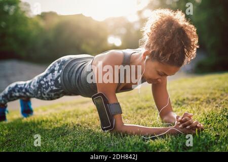 Frau, die Plank-Übung auf dem Rasen im Park macht Stockfoto