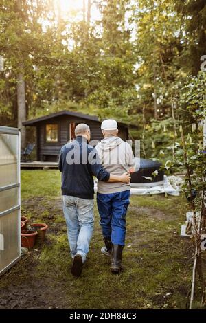 Rückansicht von Homosexuell Mann zu Fuß mit Arm um Partner Im Garten Stockfoto