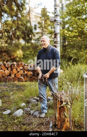 Lächelnd Homosexuell Mann hält Gartenhandschuhe beim Gehen auf Feld Stockfoto