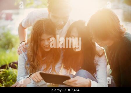 Glückliche Teenager, die am sonnigen Tag zusammen ein digitales Tablet nutzen Stockfoto