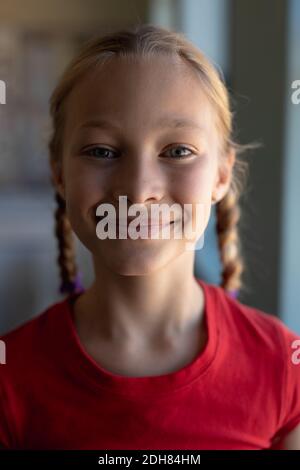 Schulmädchen mit blonden Haaren in Zöpfen, die in einem Grundschul-Klassenzimmer zur Kamera schauen Stockfoto