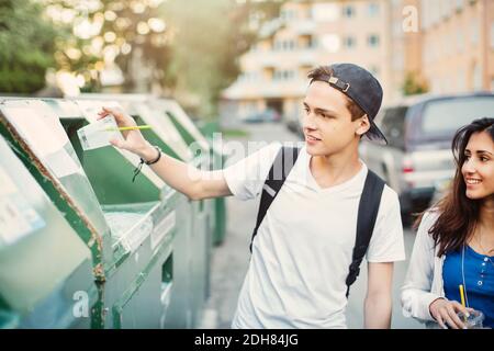 Teenager, der Einwegglas auf der Straße in den Abfalleimer legte Stockfoto