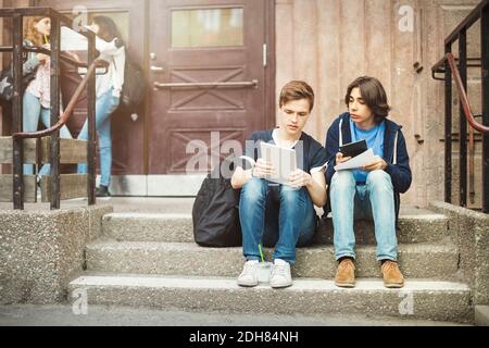 Männliche Jugendliche mit digitalen Tablet, während auf Treppen im Freien sitzen Stockfoto