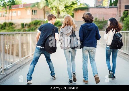 Rückansicht von Teenagern, die auf der Brücke in der Stadt spazieren Stockfoto