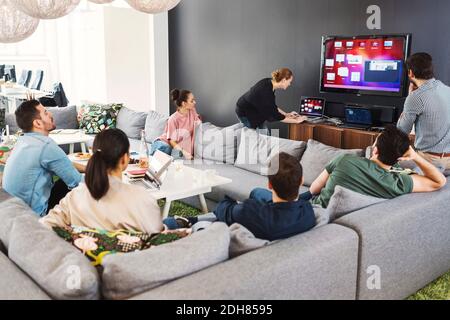 Geschäftsleute beobachten eine Kollegin, die in der Bürolobby eine Präsentation vorführt Stockfoto