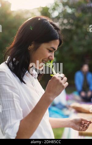 Seitenansicht einer glücklichen jungen Frau, die beim Zubereiten Kraut riecht Essen im Hinterhof Stockfoto
