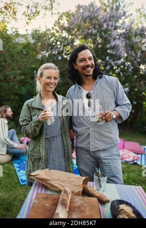 Glückliches Paar, das im Sommer mit Trinkflaschen wegschaute Party Stockfoto