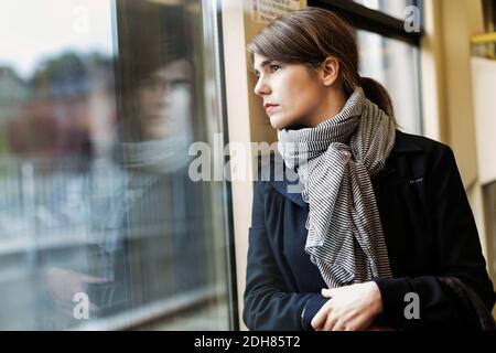 Nachdenkliche junge Frau, die durch das Straßenbahnfenster schaut Stockfoto