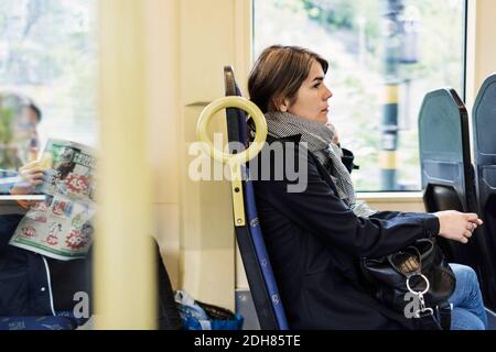 Seitenansicht einer jungen Frau, die in der Straßenbahn sitzt Stockfoto
