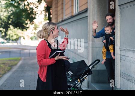 Mittlere Erwachsene Mutter winkt Familie während der Abreise zur Arbeit Stockfoto