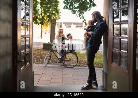 Vater an der Tür hält Baby, während die Frau verlassen Für die Arbeit Stockfoto